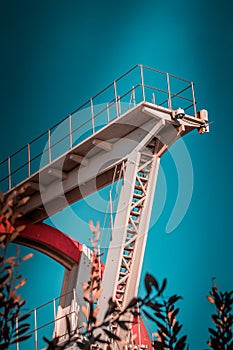 Abandoned metal diving structure. Iconic industrial and sports architecture, white and red steel elements on a deep blue clear sky