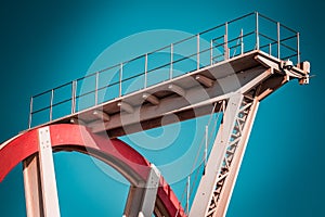 Abandoned metal diving structure. Iconic industrial and sports architecture, white and red steel elements on a deep blue clear sky