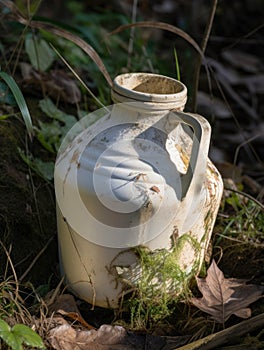 An abandoned milk jug its contents spilled and dried up in a ditch.. AI generation