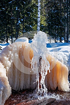 An abandoned mineral water spring in the Kemerovo region in Russia. A mass of frozen ice at a natural fountain. Winter