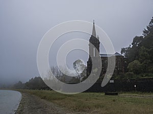 Abandoned Neogothic Chapel of Nossa Senhora das Vitorias at Furnas Lake bank in misty day, Sao Miguel, Azores, Portugal