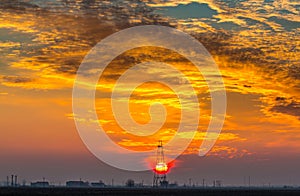 Abandoned oil and gas rig profiled on dramatic evening sky