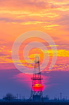 Abandoned oil and gas rig profiled on dramatic evening sky