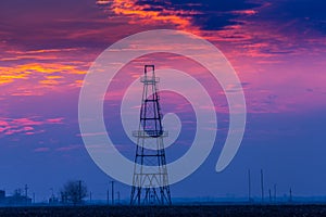 Abandoned oil and gas rig profiled on dramatic evening sky