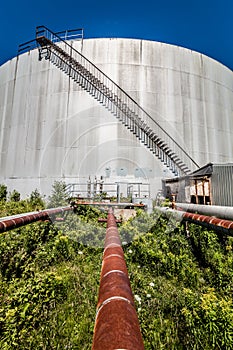 Abandoned Oil Refinery Gas Tank and Rusty Pipeline