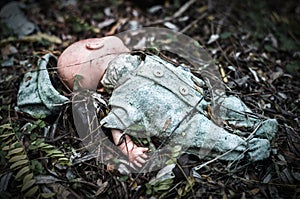 Abandoned old broken baby doll rots in scary forest