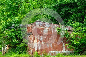 Abandoned old buildings in the forest covered with rusty sheets of tin