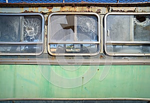 Abandoned old bus side view. Vintage pattern with peeled paint and broken glass