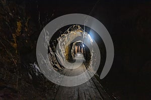 Abandoned old coal mine interior. Dangerous tunnels full of dirt and rusty equipment. Metal and wooden timbering