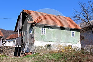 Abandoned old family house with broken roof tiles and cracked front wooden porch disconnected from power grid with hanging