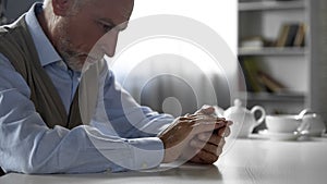 Abandoned old gentleman sitting at kitchen table, widower suffering loneliness