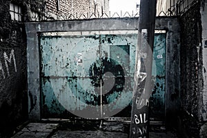 An abandoned old and grunge gate with blue colour in alley photo taken in Jakarta Indonesia