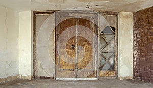 Abandoned old grunge wooden double leaves door and brown stone bricks wall