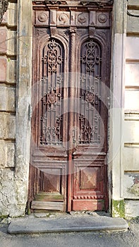 Abandoned old red door with scratched wooden panels and ornate gratings
