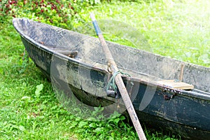 Abandoned old rowing boat with a paddle on green grass