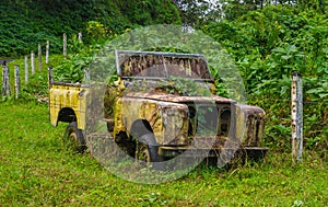 Abandoned old and rusted car decaying in the middle of the green rain forest in Volcan Arenal in Costa Rica