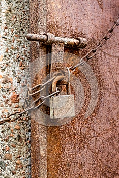 Abandoned old rustic lock with a chain on a metal door close up shot