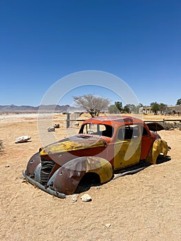 Abandoned old rusty car. Body of a retro car in the sands. Desert in Namibia.