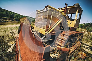 An abandoned old tractor with a bucket on a stone quarry. Old tractor in the field