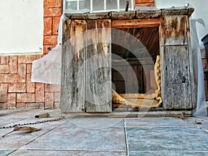 Abandoned old wood dog house with notable texture and brick wall background