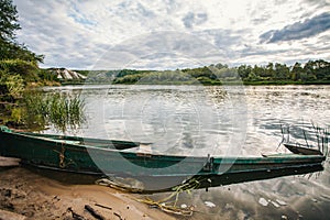 abandoned old wooden fishing boat near pier in summer lake or river. beautiful summer sunny day or evening