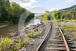 Abandoned, overgrown railroad train tracks along a rural river repurposed as trails for rail bikes in the Catskill Mountains of Ne