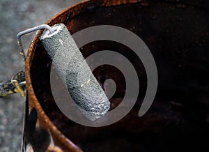 Abandoned paint roller in rusty barrel