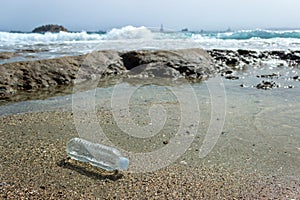 An abandoned plastic water bottle is lying on the beach.