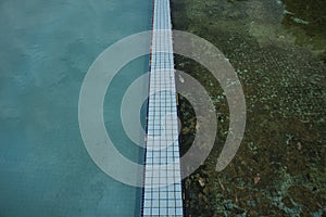 Abandoned pools at a resort, one still clean, one with the floor recover of algae