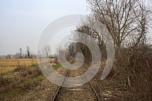 Abandoned railroad track next to a cultivated field in the italian countryside in winter