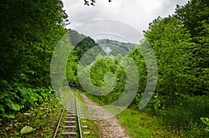 Abandoned railway in summer mountain forest with foliar trees in Gaucasus, Mezmay