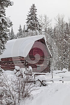 Abandoned red barn in winter scene covered in snow