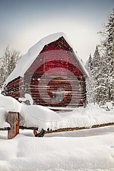 Abandoned red barn in winter scene covered in snow