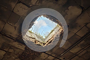 Abandoned rooftop damaged ceiling reveals cloudy sky through hole