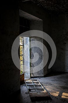 Abandoned room broken door and dramatic bright sunlight entering the place