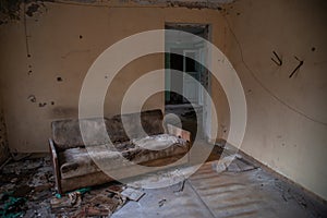 Abandoned room with old ugly couch in the building located in the Chernobyl ghost town