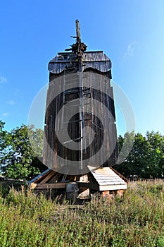 Old ruined abandoned wooden windmill tower in Drewnica with trees in the background