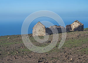 Abandoned ruins of farm house at flat plateau on top of La Merica mountain with cacti, stones and sea view. valle Gran