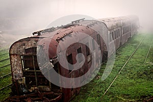 Abandoned rusting train and empty train tracks photographed in a foggy day