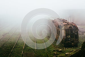 Abandoned rusting train and empty train tracks photographed in a foggy day