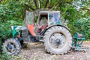 An abandoned rusty and camouflage vintage tractor. Tractor in mud.