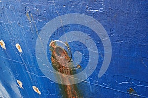 Abandoned and rusty limber hole on the side of docked ship outside. Closeup of rust stained hawsehole used for draining