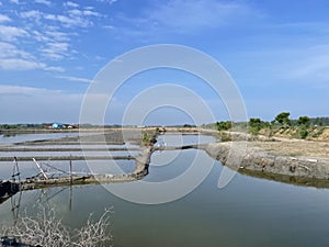 Abandoned salt ponds submerged in water with a backdrop of hills and blue sky