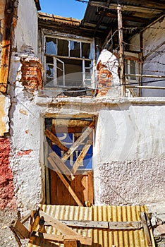 Abandoned shack house with barred shut door and broken glass window