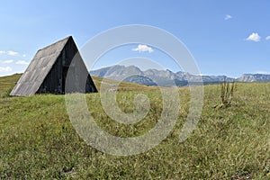 The abandoned shepherds traditional wooden hut and the Durmitor mountain in the distance