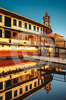 An abandoned ship is on the water. The reflection on the water. Sunset.