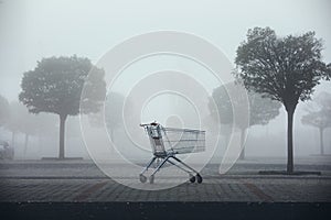 Abandoned shopping cart on parking lot in thick fog