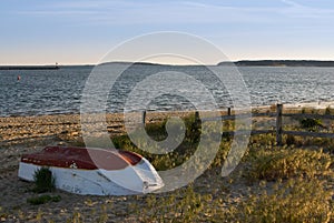 Abandoned small fishing boat on beach at sunset