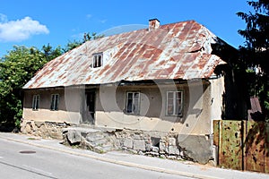 Abandoned small urban family house on broken stone and concrete foundation with damaged facade around destroyed windows