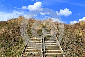 Abandoned stairs overgrown, leading to the blue sky with clouds. Concept of stairway to Heaven or thorny path to the beautiful.